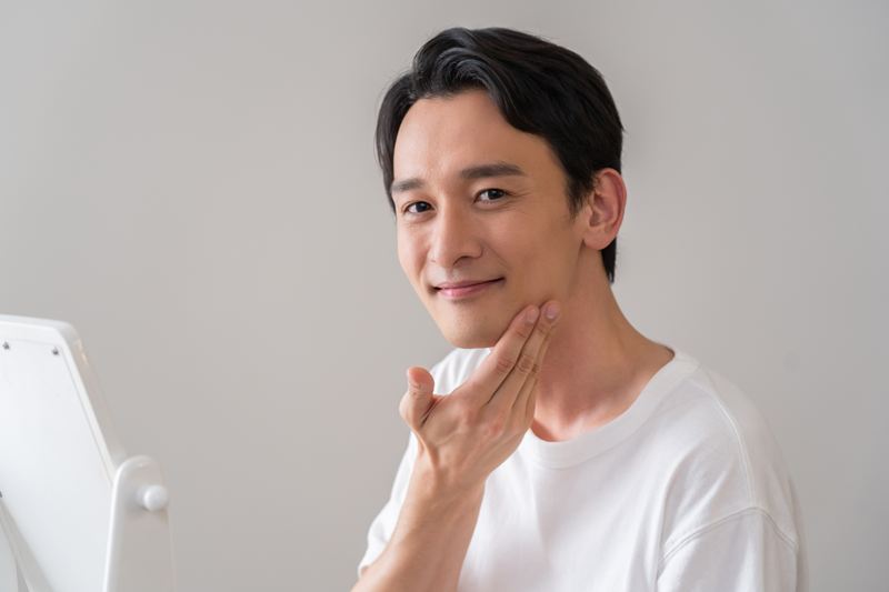正しい保湿と内側からのケアで、適度な潤いと健康的なツヤを手に入れた男性。肌が整ったことで「清潔感」と「余裕」が生まれ、明るい表情で自信を取り戻したポジティブな姿。