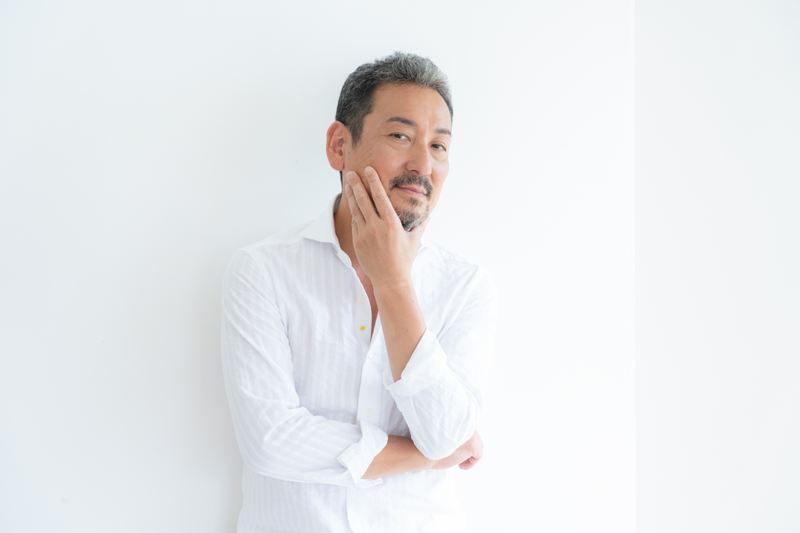正しいスキンケア習慣によって適度な潤いとツヤを纏い、自信に満ちた表情を見せる40代男性。シワやたるみをケアすることで「疲れた印象」から「余裕のある大人」へと第一印象が変わり、清潔感と信頼感を醸し出しているポジティブな姿。