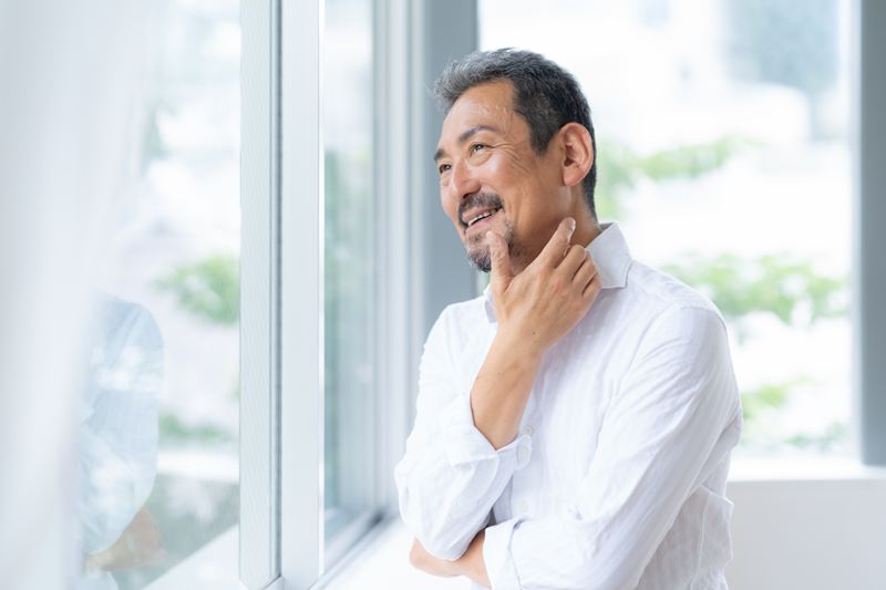適度なうるおいとツヤのある肌で、自信を持って身なりを整える男性。「余裕のある大人」の清潔感を醸し出し、周囲に信頼感を与えるような、整った肌質を象徴するイメージ。