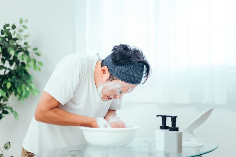 両手いっぱいの泡で顔を包み込むように洗う男性。